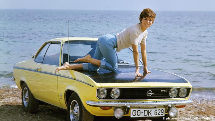 ألمانيا، سيارة أوبل مانتا، امرأة ترتدي الجينز وتستعرض على غطاء المحرك.
