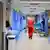 A man in red scrubs walks through a hospital ward