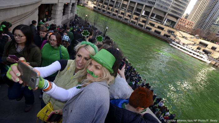 Personas disfrazadas se toman un selfie ate el río coloreado de verde, en Chicago.