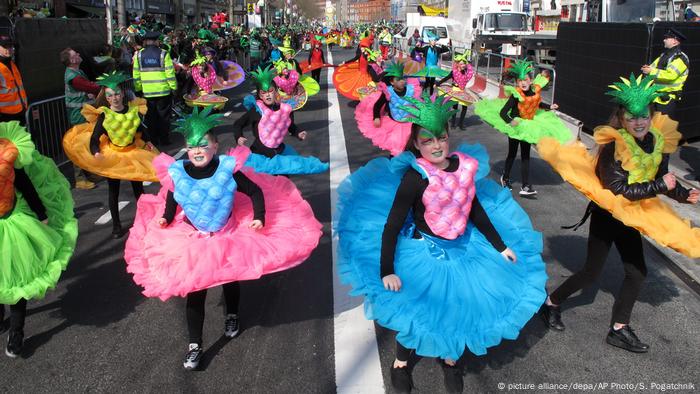 Personas con coloridos disfraces marchan en un desfile de St. Patrick's Day.