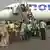 Would-be migrants descend the staircase of a chartered plane 