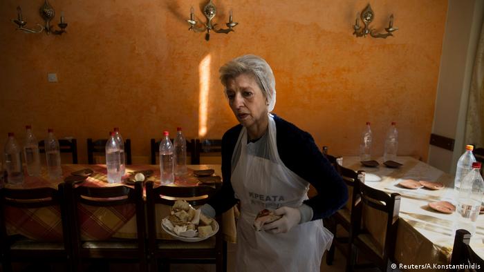 Retired teacher and volunteer Eva Agkisalaki clears tables at a soup kitchen run in Athens.