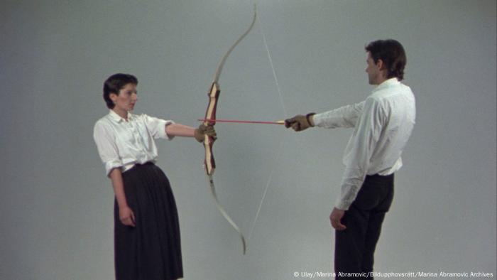 Marina Abramovic und Ulay stehen sich gegenüber und halten jeweils eine Seite eines Bogens in der Hand. Der Pfeil ist auf sie gerichtet, er spannt die Sehne des Bogens. (Ulay/Marina Abramovic/Bildupphovsrätt/Marina Abramovic Archives)
