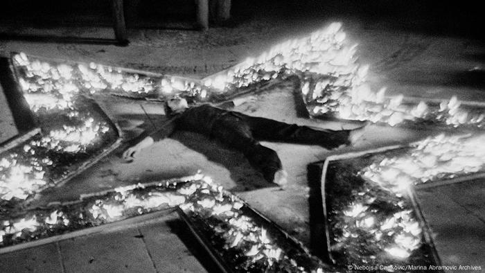 Marina Abramovic liegt, Arme und Beine von sich gestreckt, bei ihrer Performance Rhythm 5 in der Mitte eines brennenden Sterns auf dem Boden. (Nebojsa Cankovic/Marina Abramovic Archives)