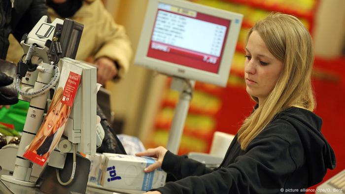 A cashier sits at a supermarket checkout.  (picture alliance/dpa/O. Berg)