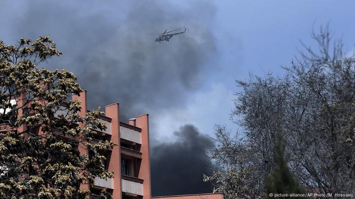 Against a backdrop of black smoke, a helicopter flies over a military hospital in Kabul (picture-alliance/AP Photo/M. Hossaini)