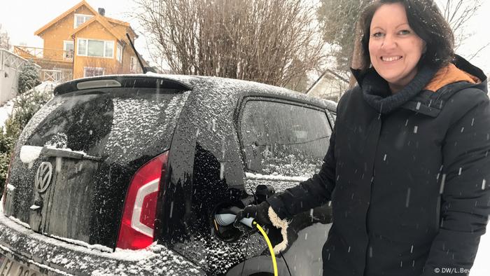 A woman charges her electric car