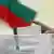 Избиратель в Болгарии опускает в урну избирательный бюллетень 