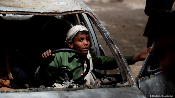 Un niño juega en un coche quemado en la capital yemení.