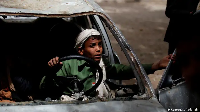 Un niño juega en un coche quemado en la capital yemení.