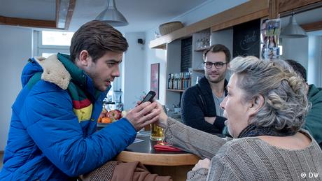 Eine ältere Frau zeigt einem jungen Mann ihr Smartphone.