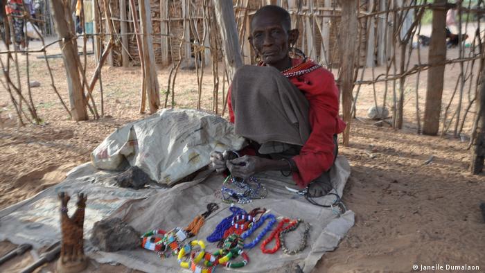 A woman threads colored beads on the ground