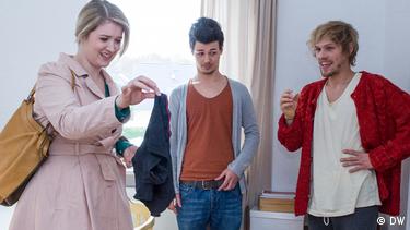 A woman holds a pair of underwear up with two fingers. Nawin looks at the floor and Sebastian laughs.