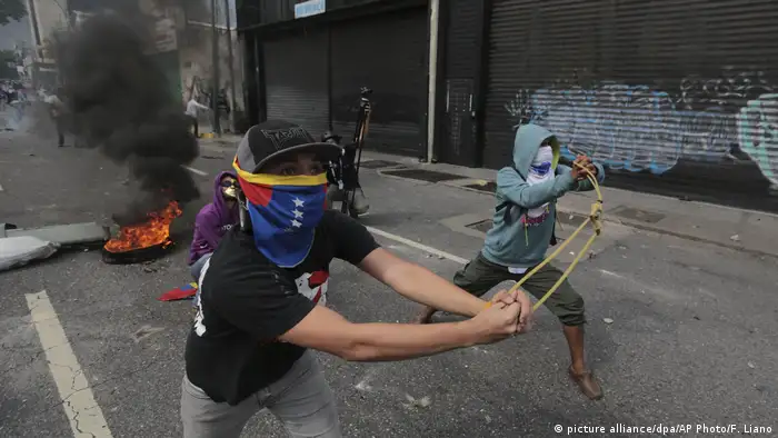 Демонстранты бросают камни в сотрудников полиции, Каракас, 19 апреля 2017 г.