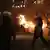 Policajac s kacigom i štitom ispred vatre na ulici Atene