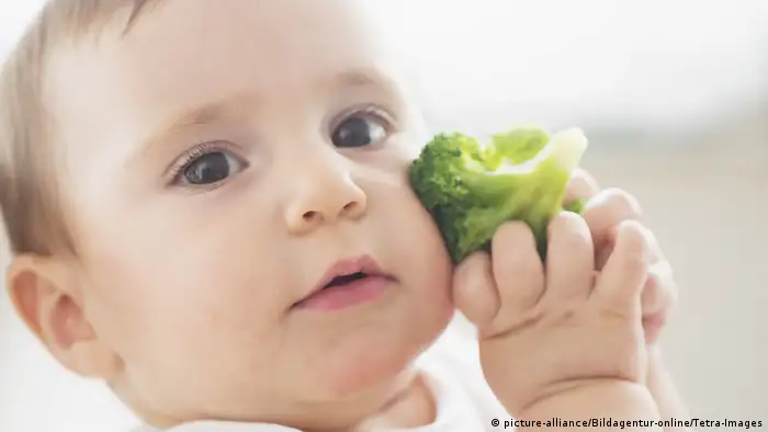 Baby (12-17 Monate) haelt Brokkoli, Baby girl (12-17 months) holding broccoli