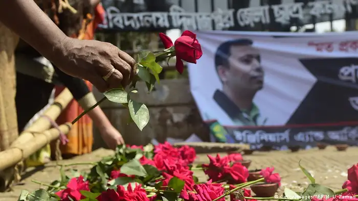 Ein Mann legt eine rote Rose zu vielen weiteren Rosen, die vor dem Porträt des ermordeten Bloggers Avijit Roy aufgereiht wurden. (Foto: Getty Images/AFP/M. U. Zaman)