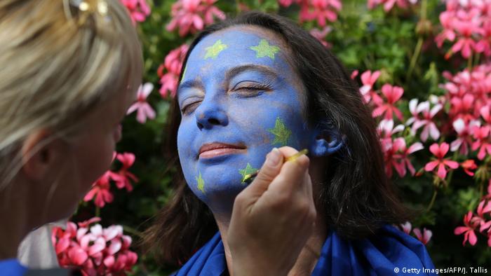 Eine junge Frau lässt ihr Gesicht in den Farben Europas schminken