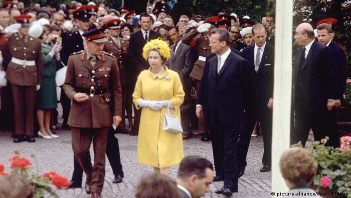 Queen Elizabeth II visits Germany in 1965, wearing a yellow dress. 