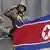 A North Korean national flag flutters as soldiers in tanks salute