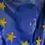 Two elderly women pass by a European Union flag in Belgrade
