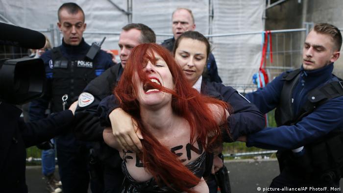 Полицейские сдерживают женщину из движения Femen