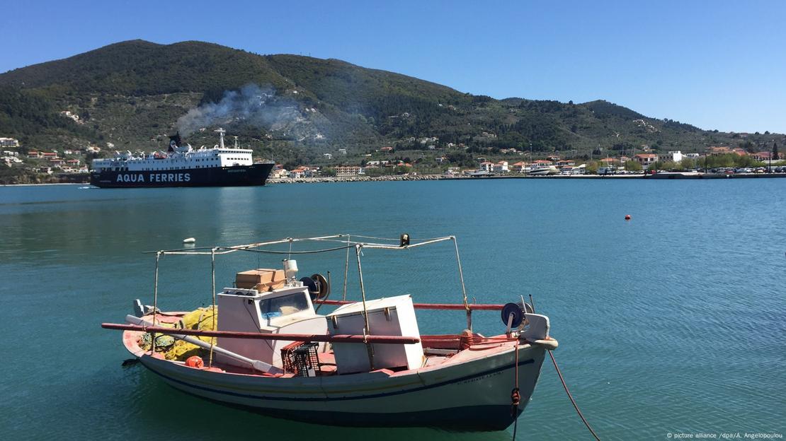 Μία βάρκα στη Σκόπελο, ενώ στο βάθος διακρίνεται ένα φέρι-μποτ