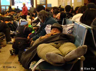 一位农民工躺在火车站的椅子上等回家过年