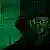 Человек в черном капюшоне на фоне компьютерных кодов