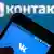 Смартфон с логотипом "Вконтакте" на фоне большого логотипа соцсети