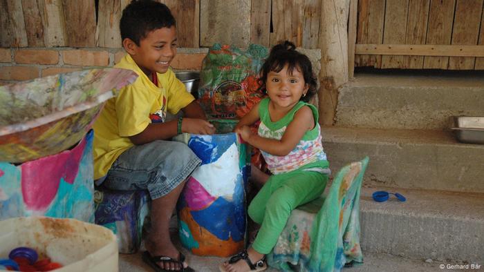 Dos niños mexicanos juegan con objetos creados a partir de basura plástica reciclada.