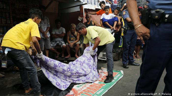 Filipino funeral parlor workers carry a dead body following a police operation against illegal drugs in Manila, Philippines, 10 November 2016