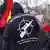 Ativista em protesto de extrema direita com casaco escrito nas costas: "Se não nos protegem, nos protegemos nós mesmos"