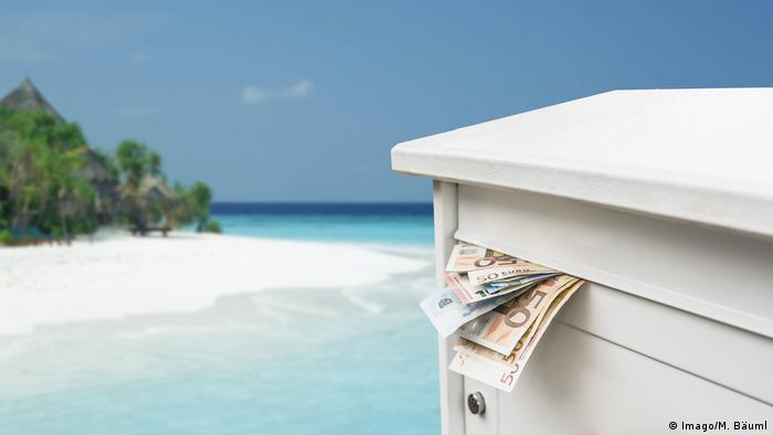 a letterbox stuffed with money against island backdrop