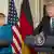 Angela Merkel e Donald Trump em púlpitos, diante de bandeiras dos EUA e Alemanha