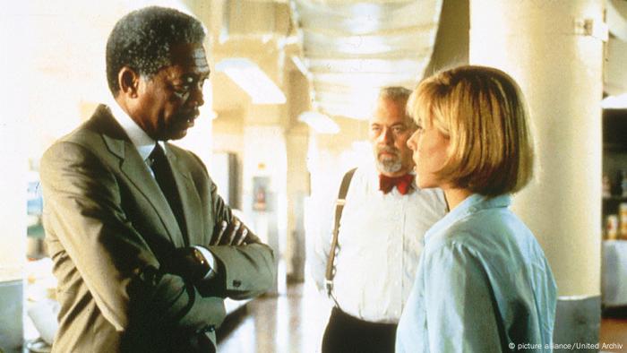 Still from 'Deep Impact': Morgan Freeman with his arms crossed speaks to a woman while another older man listens.