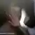 Shadowy image of a woman holding holding her hand to her face and a fisth approaching