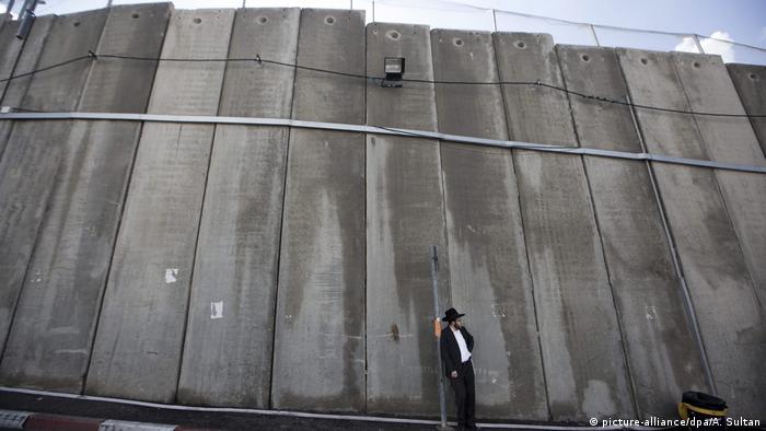 A solitary man stands of Israel's concrete separation barrier