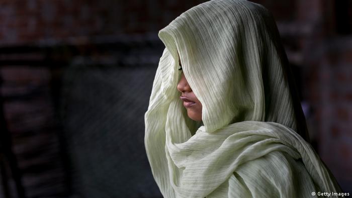 A woman, her face hidden, wearing a white scarf