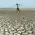 An Indian man walks over the parched bed of a reservoir on the outskirts of Chennai