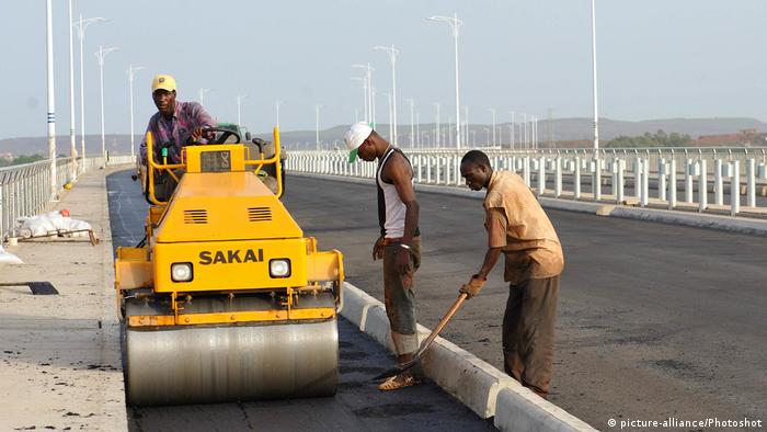 Three men use a paving machine to tar a road in Mali's capital Bamako