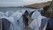 A migrant walks among tents at a beach outside a refugee camp next to the water on Chios A migrant walks among tents at a beach outside a refugee camp next to the water on Chios