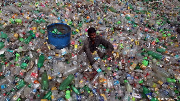 A man sorts bottles at a plastic junkyard