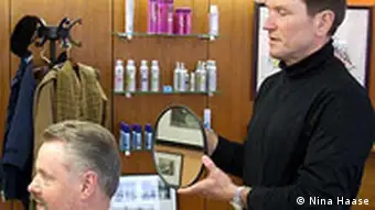 Friseur Udo Muench steht hinter einem Kunden im Behandlungsstuhl