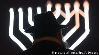 Силуэт еврея в шляпе на фоне меноры