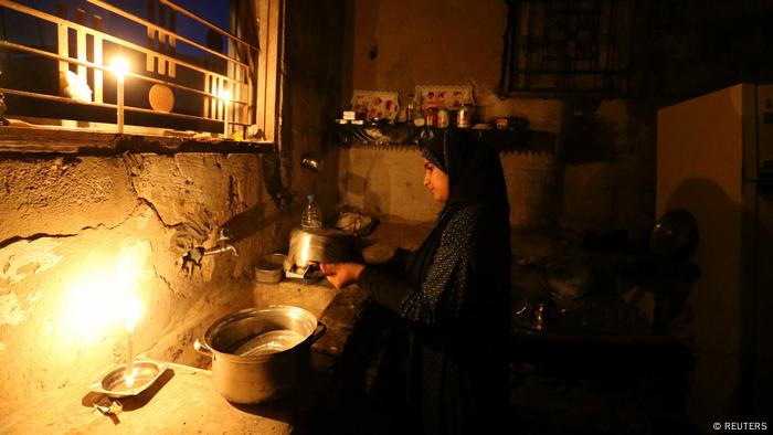 Ein Mädchen spült bei Kerzenlicht ab (Foto: Reuters)