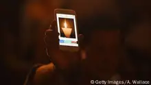A participant holds up a smartphone showing an animated GIF image of a vigil candle as he and others attend a candlelight vigil at Hong Kong's Victoria Park on June 4, 2017, to mark the 28th anniversary of the 1989 Tiananmen crackdown in Beijing. Thousands gathered at a candlelit vigil in Hong Kong on June 4 to mark 28 years since China's bloody Tiananmen Square crackdown but the annual event is struggling for support among younger generations. / AFP PHOTO / Anthony WALLACE (Photo credit should read ANTHONY WALLACE/AFP/Getty Images)