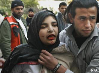 A Palestinian assists a wounded woman, who according to Palestinian medical sources was injured in an Israeli strike, into Kamal Adwan hospital, in the northern Gaza Strip town of Beit Lahiya, Monday, Jan. 12, 2009