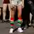 People's legs, some bare, one wears colorful striped knee socks