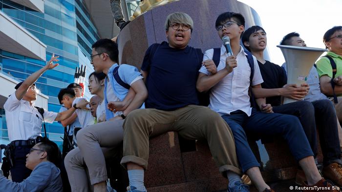 Pro-democracy activist Joshua Wong (4th R) chants slogans in front of the Golden Bauhinia sculpture during a protest to demand full democracy in Hong Kong